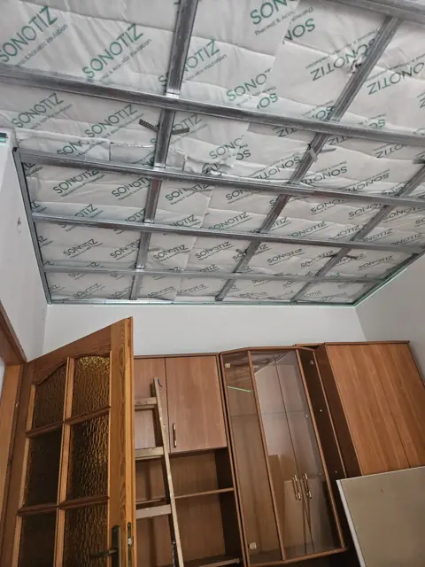 Ruszt sufitu podwieszanego w pokoju z zabezpieczonymi meblami